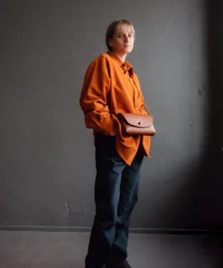 a man in an orange shirt is holding a brown bag.