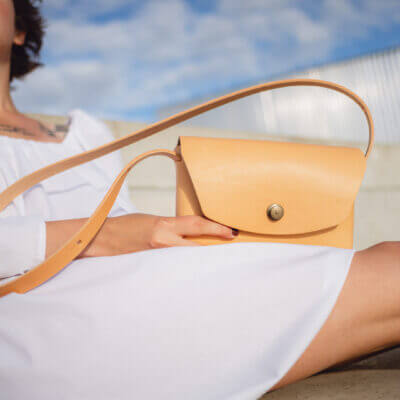 a woman in a white dress holding a tan purse.