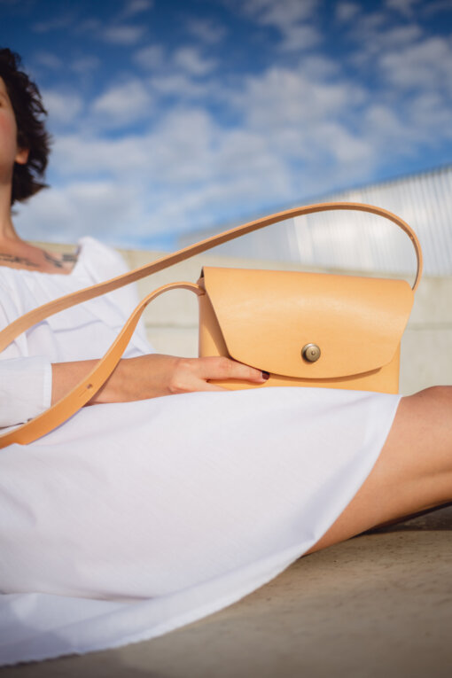 a woman in a white dress holding a tan purse.