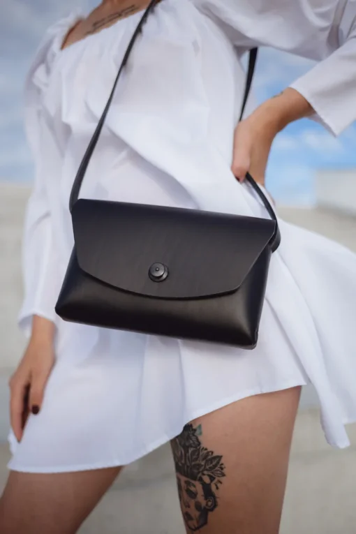a woman in a white dress holding a black purse.