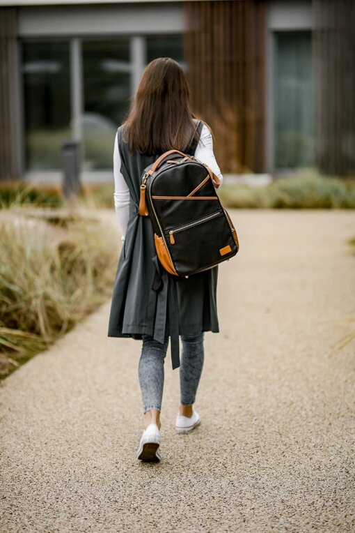 a woman walking down a path carrying a backpack.