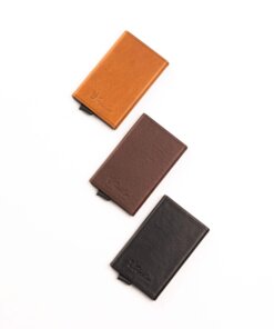 three different colored leather wallets on a white surface.