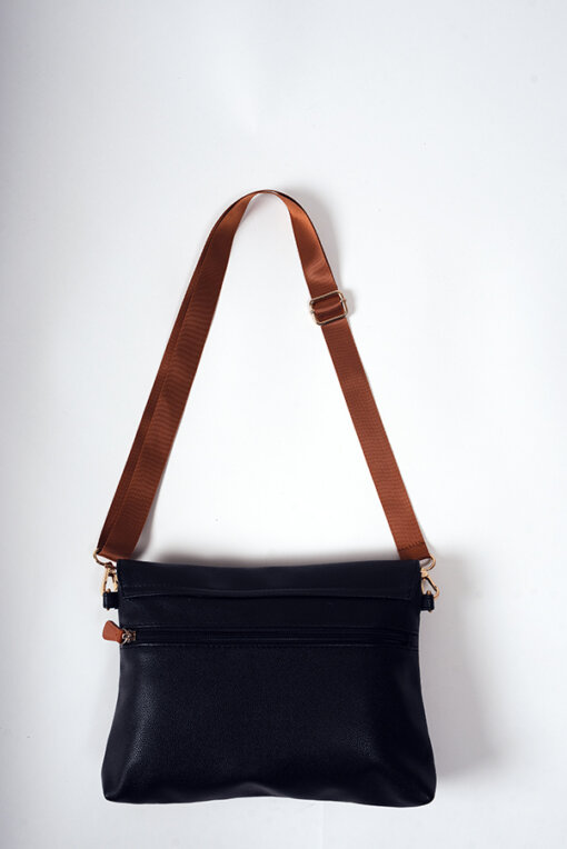 a black purse with a brown strap hanging on a wall.