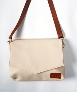 a white purse with a brown strap hanging on a wall.