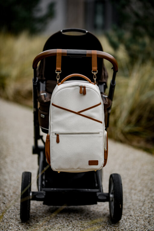 a white backpack sitting on top of a stroller.
