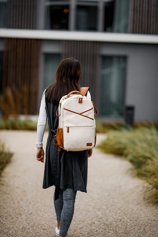 a woman walking down a path carrying a white backpack.