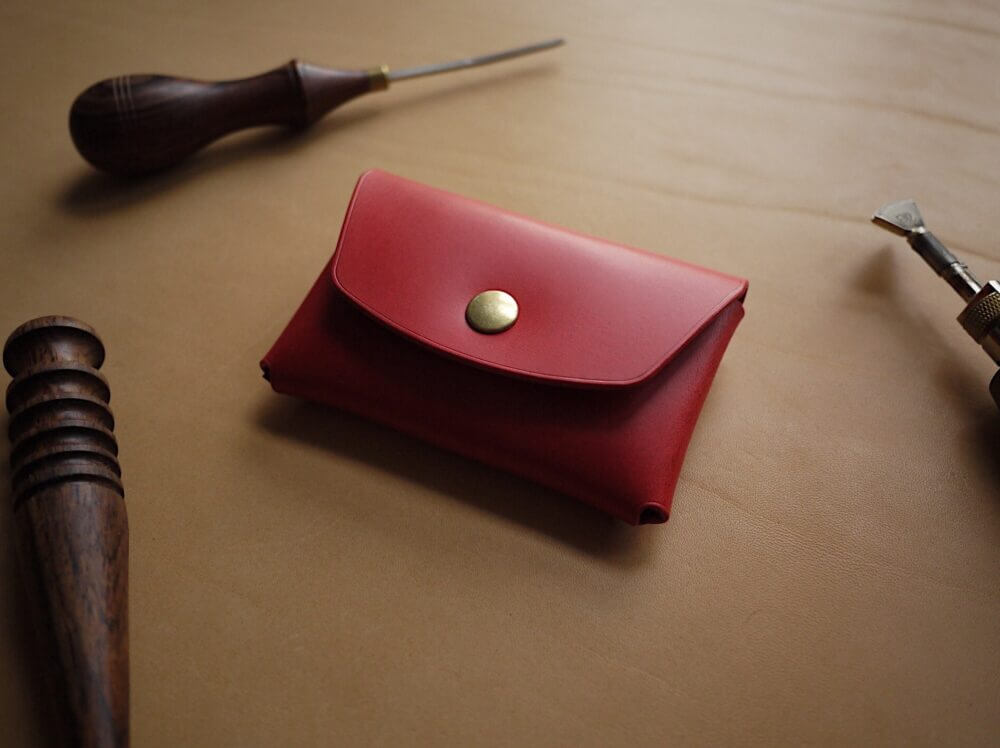 a red wallet sitting on top of a table next to a hammer.