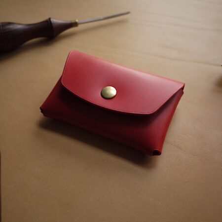 a red wallet sitting on top of a table next to a hammer.