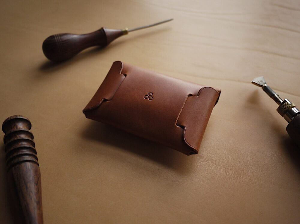 a leather case sitting on top of a table next to a pair of scissors.
