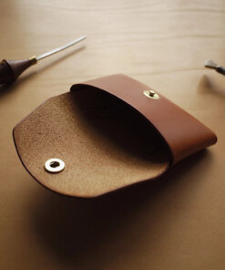 a leather case sitting on top of a table next to a pair of scissors.