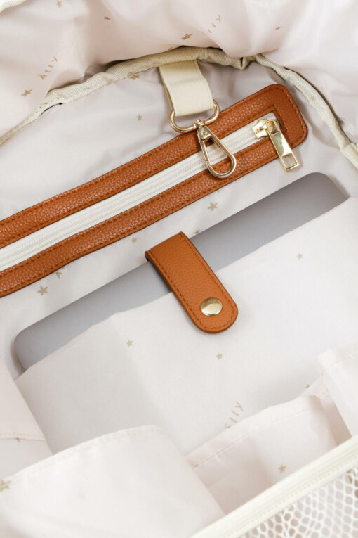 a brown and white purse sitting on top of a bed.