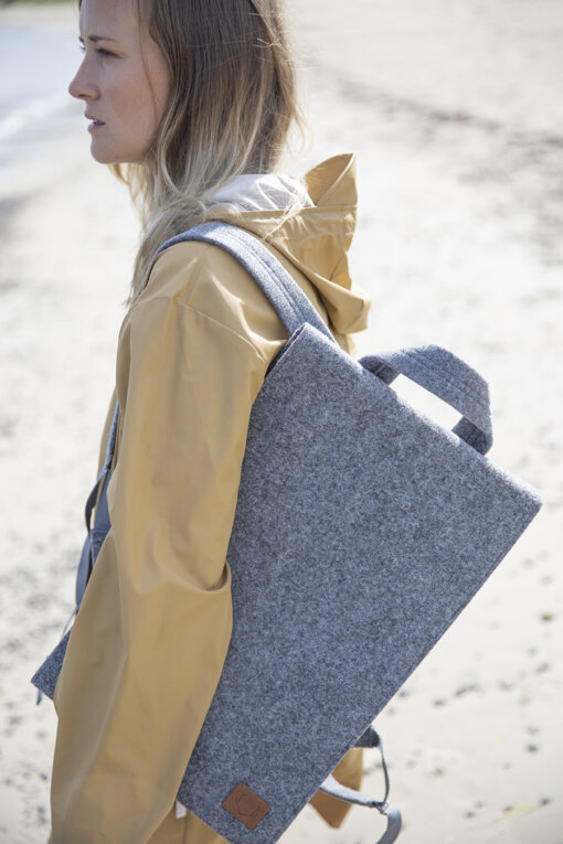 a woman carrying a gray bag on the beach.