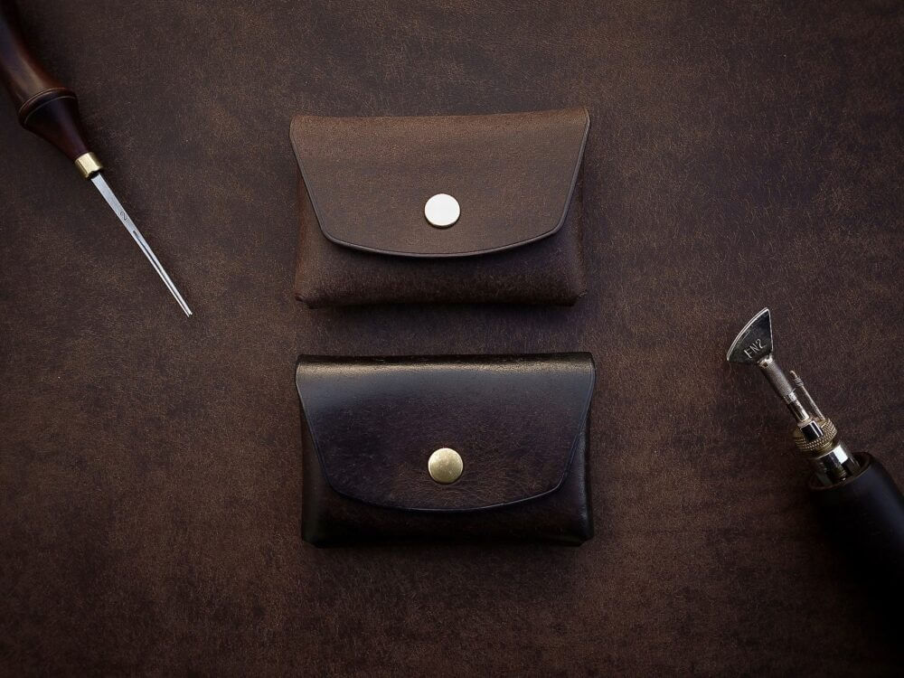 a leather case, a pen, and a knife on a table.