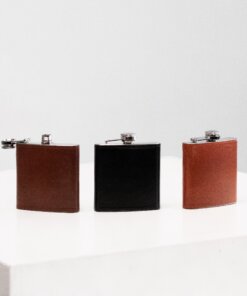 three leather flasks lined up on a white surface.