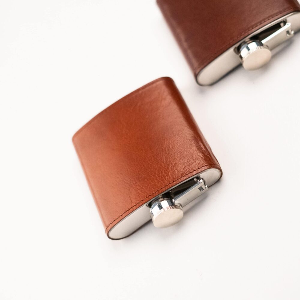 a pair of brown leather cufflinks on a white surface.