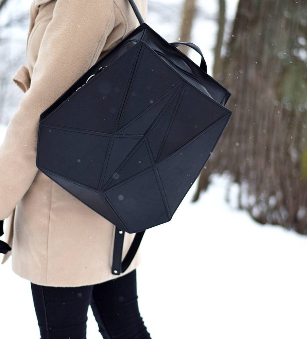 a woman walking in the snow carrying a black bag.