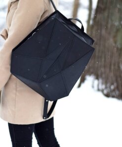 a woman walking in the snow carrying a black bag.