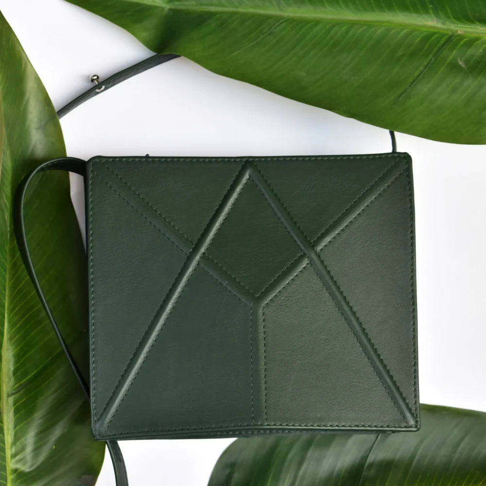 a green leather case sitting on top of a green plant.
