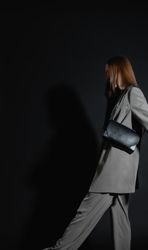 a woman in a gray suit and black handbag.