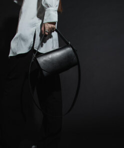 a woman in a white shirt is holding a black bag.