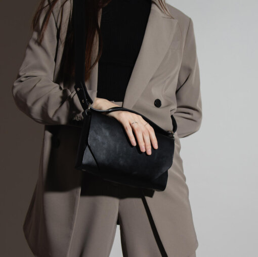 a woman is holding a black purse.