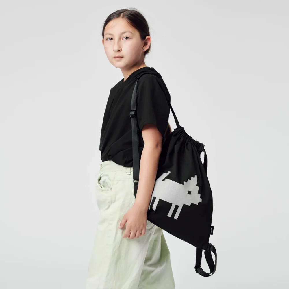 a young girl carrying a black bag with a white dog on it.