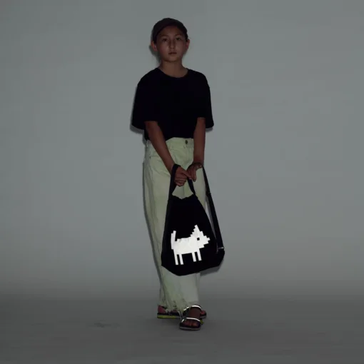 a young boy holding a black bag with a white dog on it.