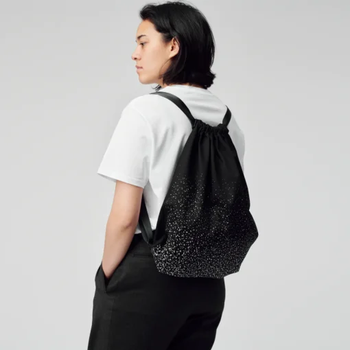 a woman in a white t - shirt is wearing a black backpack.