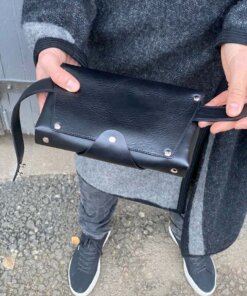 a person is holding a black leather bag.