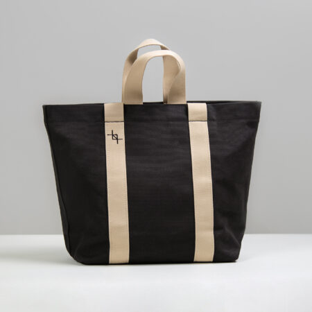 a black and beige tote bag sitting on a table.