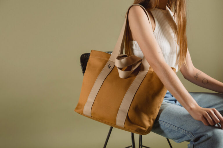 a woman sitting on a chair holding a brown bag.