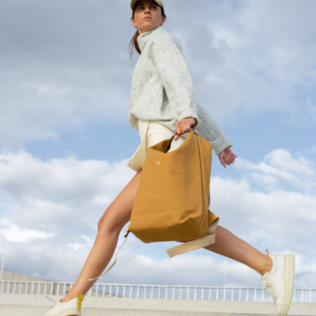 a woman in a white sweater is carrying a brown bag.