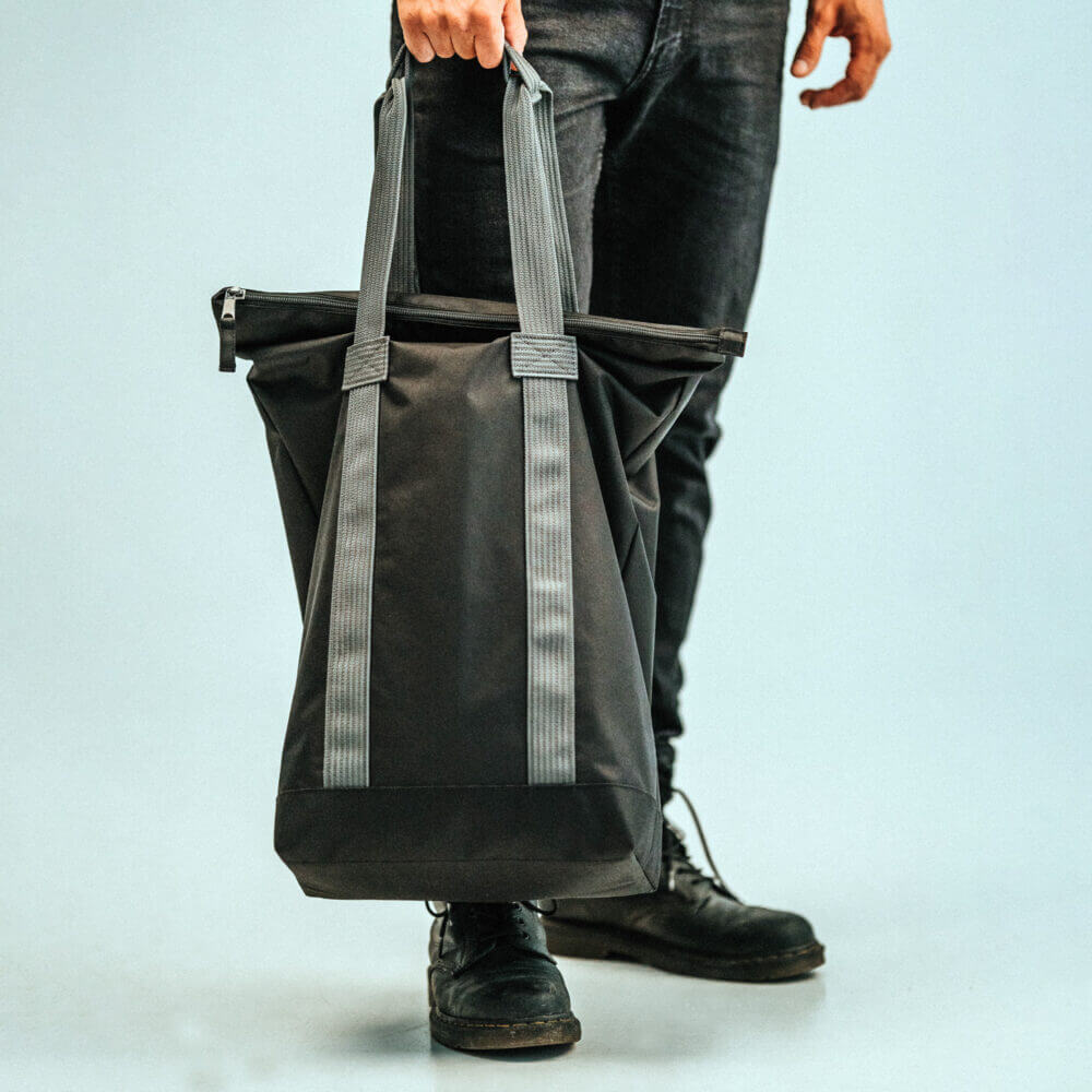 a man holding a black bag with grey straps.