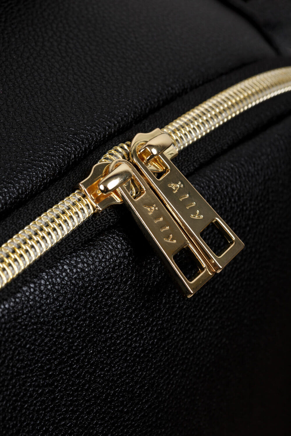 a close up of a gold zipper on a black suitcase.