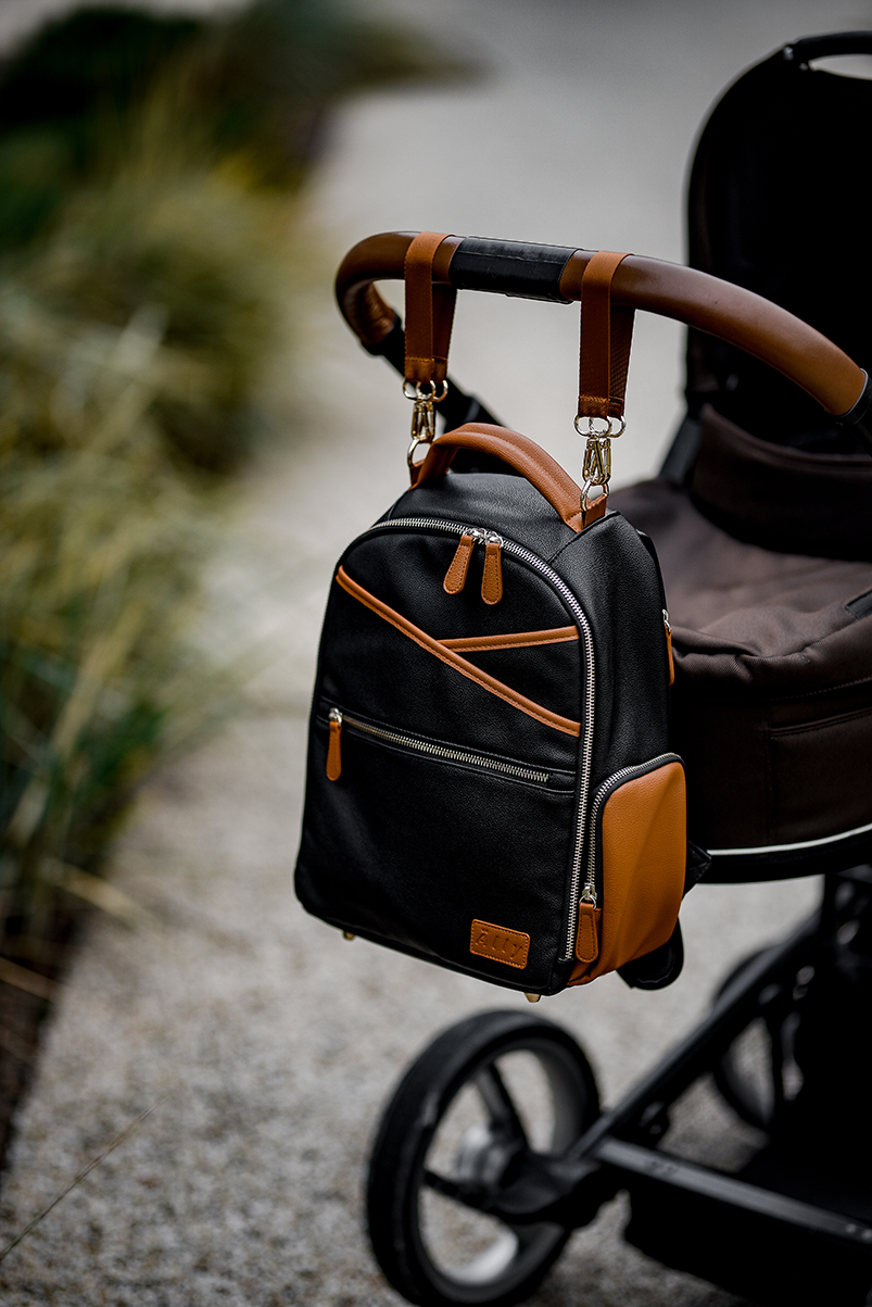 a black and brown backpack hanging from a stroller.