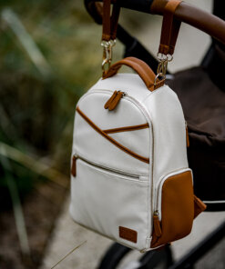 a white and brown backpack sitting on top of a stroller.