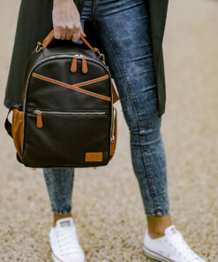 a woman holding a brown and black backpack.