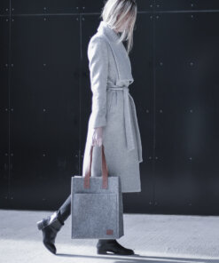 a woman in a gray coat carrying a gray bag.
