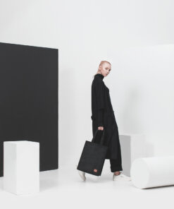 a woman with a black bag walking in a white room.