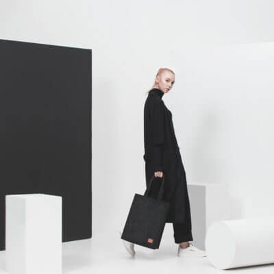 a woman with a black bag walking in a white room.