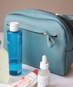 A DOUGLAS Toiletry Bag - Turquoise with a bottle of water and other items.