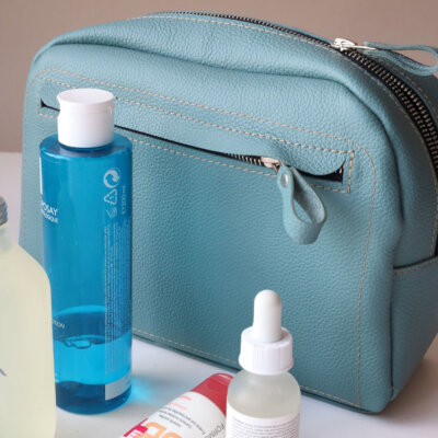 A DOUGLAS Toiletry Bag - Turquoise with a bottle of water and other items.