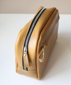 A DOUGLAS Toiletry Bag - Mustard sitting on a table.