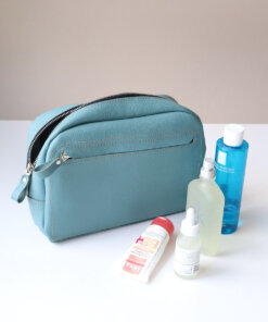 A DOUGLAS Toiletry Bag - Turquoise with cosmetics and a bottle of water.