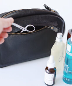 A person is holding a Douglas Toiletry Bag - Black with cosmetics in it.