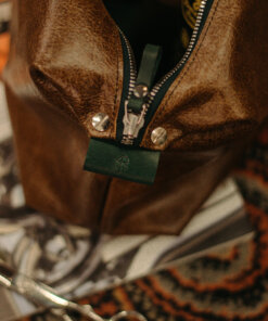 Un bolso de cuero marrón con unas tijeras.