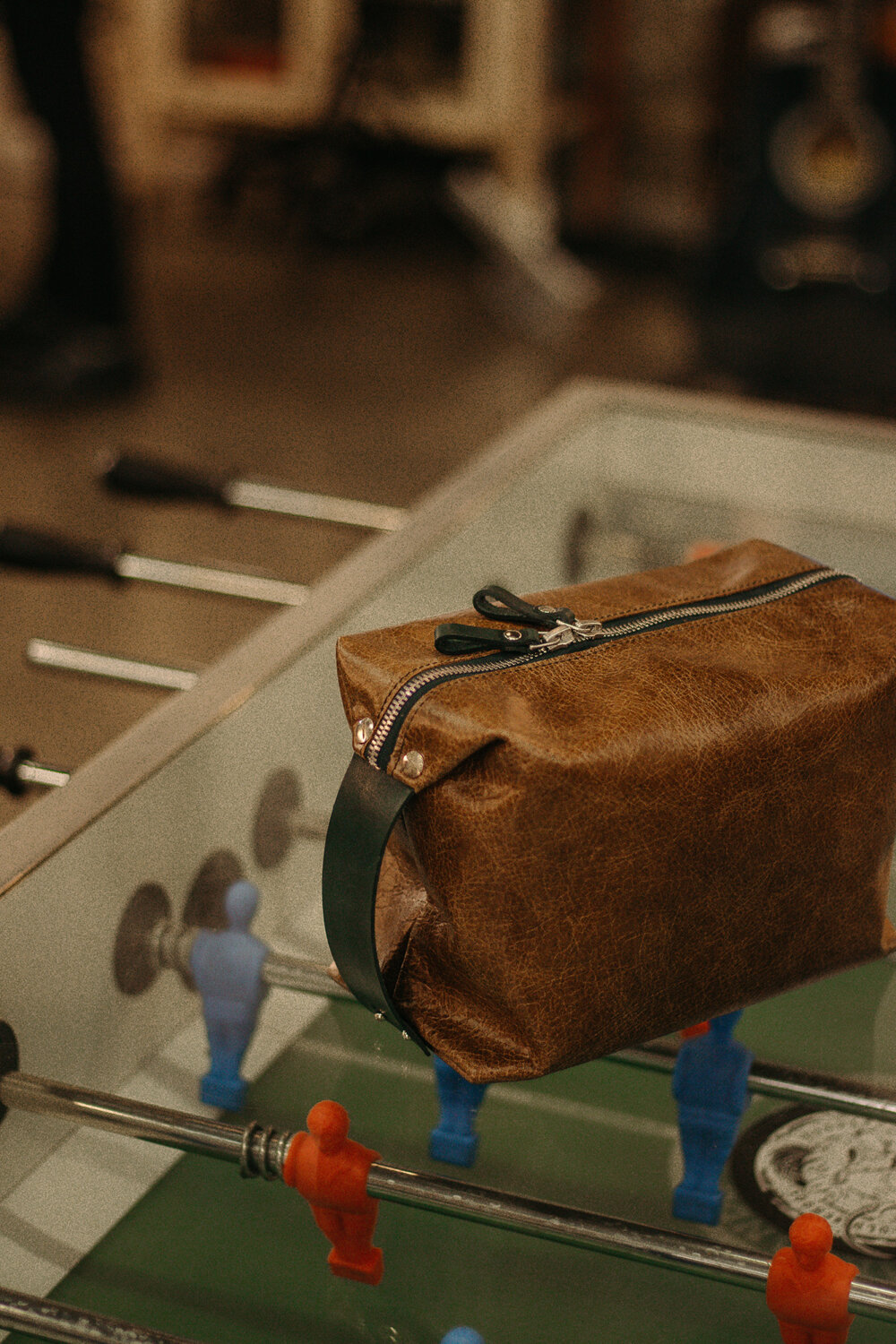 A Large Toiletry Bag Travel Mate sitting on top of a foosball table.