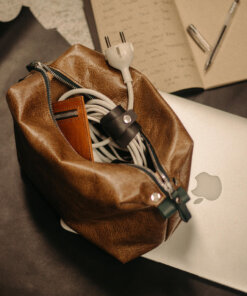 Un bolso de cuero marrón con una computadora portátil encima.