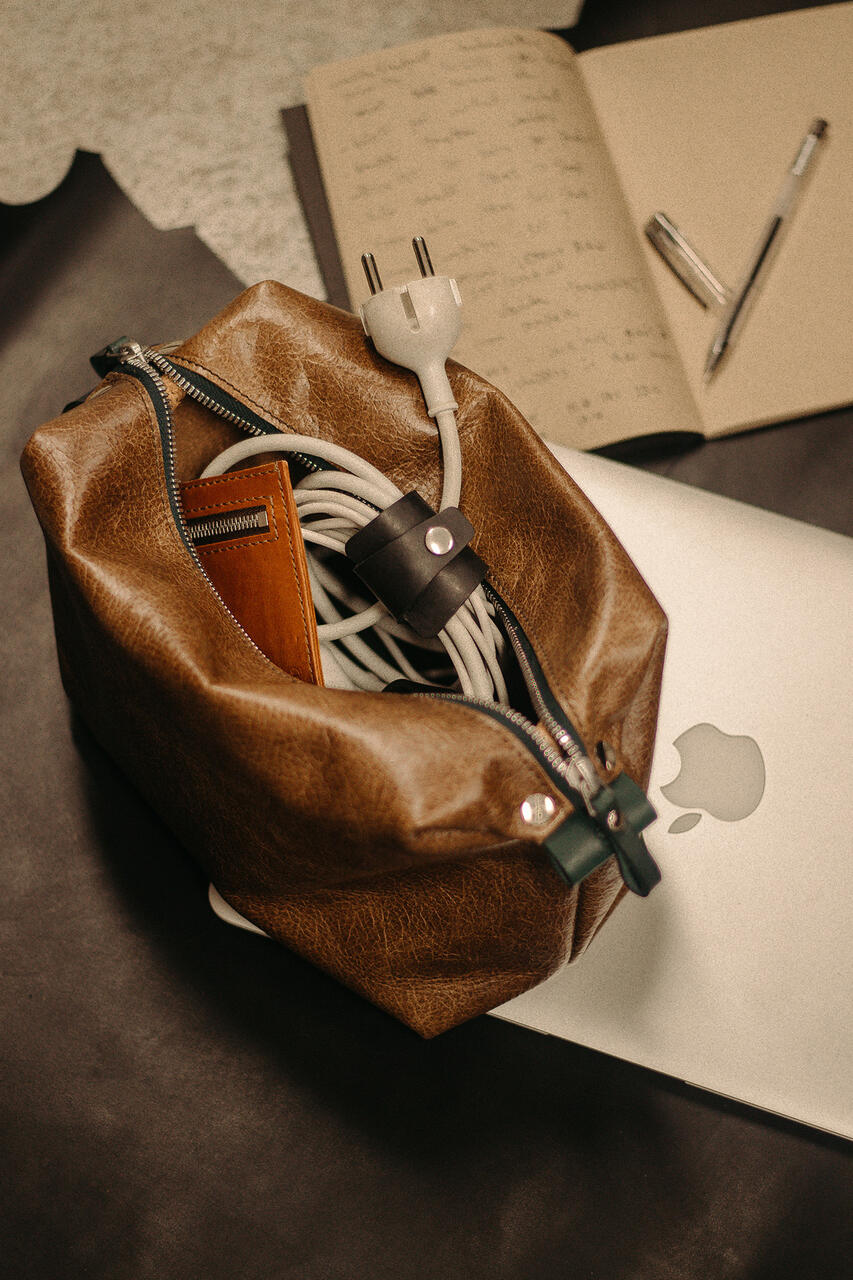 Un bolso de cuero marrón con una computadora portátil encima.