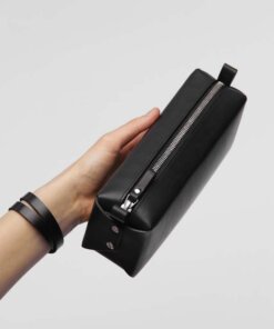 A hand holding a Big Dreamer Makeup Bag - Black case.